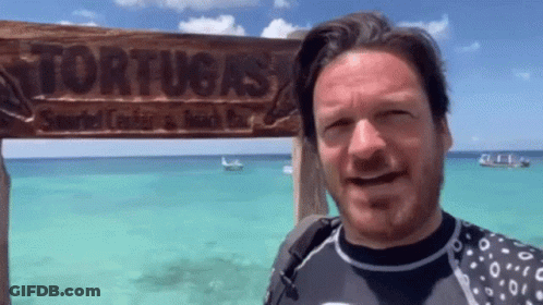 A Man Is Standing In Front Of A Sign That Says Tortuga 'S GIF