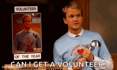 A Man Is Standing In Front Of A Sign That Says Volunteer Of The Year And Holding A Magnifying Glass . GIF