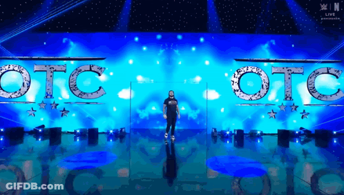 A Man Is Standing In Front Of A Stage That Says Otc On It GIF