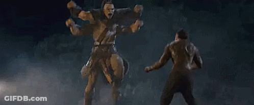 A Man Is Standing In Front Of A Statue Of A Giant Warrior . GIF