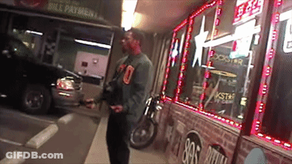 A Man Is Standing In Front Of A Store That Says Rockstar Energy Drink GIF