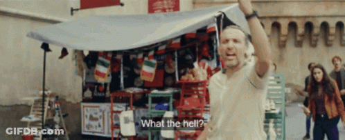 A Man Is Standing In Front Of A Store With A Sign That Says " What The Hell " GIF