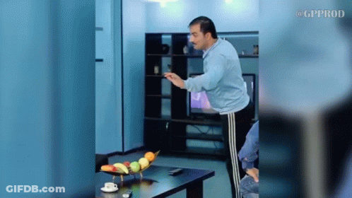 A Man Is Standing In Front Of A Table With A Bowl Of Fruit On It .. GIF