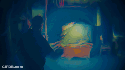 A Man Is Standing In Front Of A Television With A Glowing Light On It GIF
