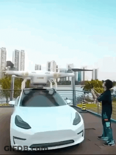 A Man Is Standing In Front Of A Tesla Model 3 With A Drone Attached To It . GIF