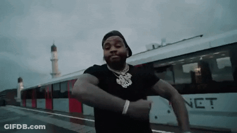 A Man Is Standing In Front Of A Train And Dancing . GIF