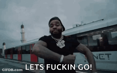 A Man Is Standing In Front Of A Train With The Words `` Lets Fuckin Go '' Written On His Face . GIF