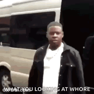 A Man Is Standing In Front Of A Van And Looking At The Camera . GIF