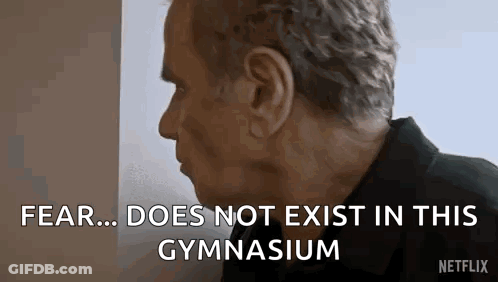 A Man Is Standing In Front Of A Wall And Talking About Fear Does Not Exist In This Gymnasium . GIF