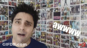 A Man Is Standing In Front Of A Wall With A Bunch Of Pictures On It And Says Awww GIF