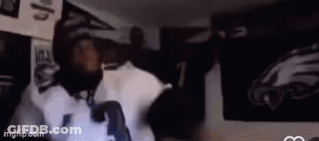 A Man Is Standing In Front Of A Wall With A Picture Of An Eagles Jersey On It . GIF