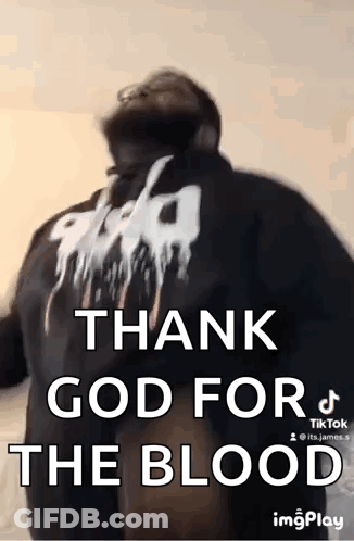 A Man Is Standing In Front Of A Wall With The Words `` Thank God For The Blood '' Written On His Back . GIF