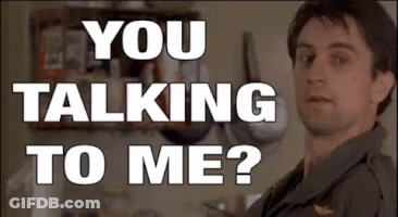 A Man Is Standing In Front Of A Wall With The Words `` You Talking To Me ? '' Written On It . GIF