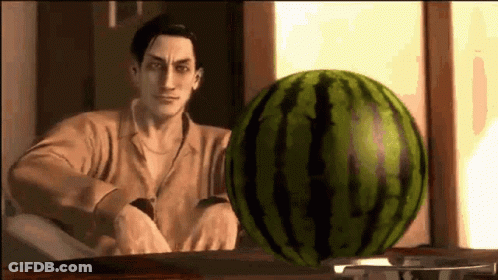 A Man Is Standing In Front Of A Watermelon On A Table . GIF