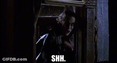 A Man Is Standing In Front Of A Window And Holding A Gun . GIF