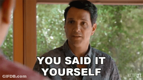 A Man Is Standing In Front Of A Window And Talking To Another Man . GIF