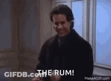 A Man Is Standing In Front Of A Window Holding A Bottle Of Rum And Saying `` The Rum '' . GIF