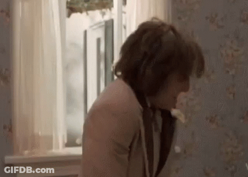 A Man Is Standing In Front Of A Window In A Room With A Floral Wallpaper . GIF