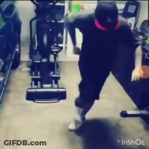 A Man Is Standing In Front Of An Elliptical Machine In A Garage . GIF