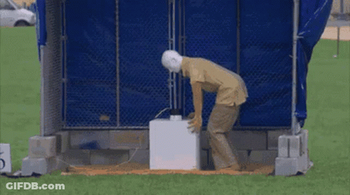 A Man Is Standing In Front Of An Explosion With Sparks Coming Out Of It . GIF
