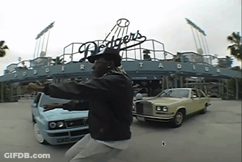 A Man Is Standing In Front Of Dodgers Stadium GIF
