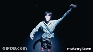 A Man Is Standing In The Dark With His Arms In The Air .. GIF