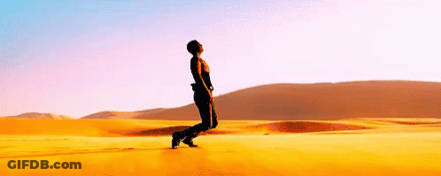 A Man Is Standing In The Middle Of A Desert Looking Up At The Sky . GIF