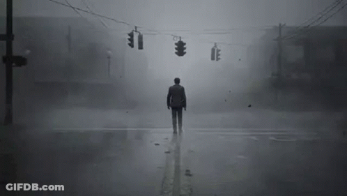 A Man Is Standing In The Middle Of A Foggy Street At An Intersection . GIF