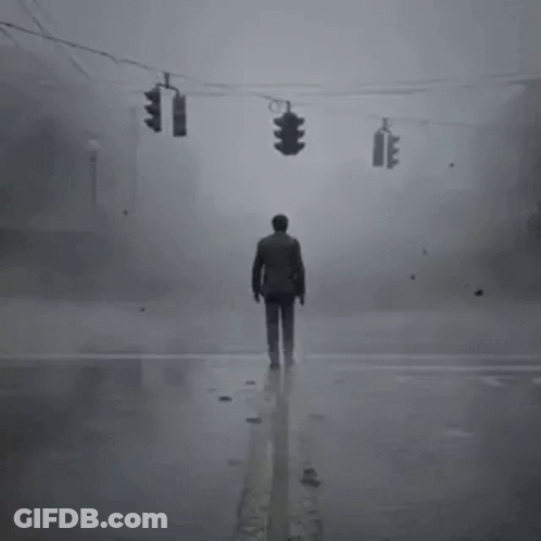 A Man Is Standing In The Middle Of A Foggy Street . GIF
