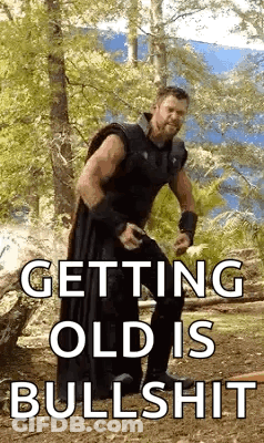A Man Is Standing In The Woods With The Words `` Getting Old Is Bullshit '' . GIF
