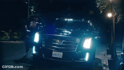 A Man Is Standing Next To A Black Cadillac With A California License Plate GIF