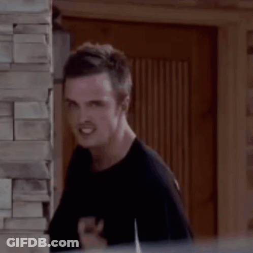 A Man Is Standing Next To A Brick Wall And Making A Funny Face With His Finger In His Mouth . GIF