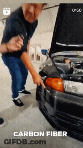A Man Is Standing Next To A Car With The Hood Open And The Words Carbon Fiber Written Below Him GIF
