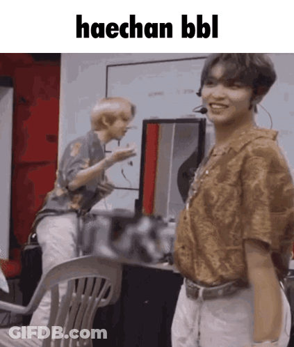A Man Is Standing Next To A Chair With The Words Haechan Bbl Written On It . GIF