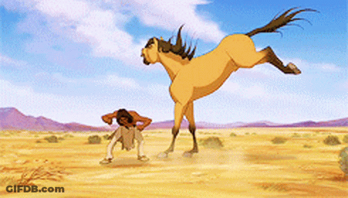 A Man Is Standing Next To A Large Horse In The Desert GIF