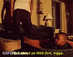 A Man Is Standing Next To A Little Boy Who Is Laying On A Couch And Says " Fuck About Yo Little Fort Nigga " GIF