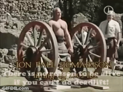 A Man Is Standing Next To A Pair Of Wagon Wheels With The Words Jon Pall Sigmarsson Written On The Bottom GIF