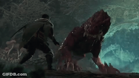 A Man Is Standing Next To A Red Monster In A Cave . GIF