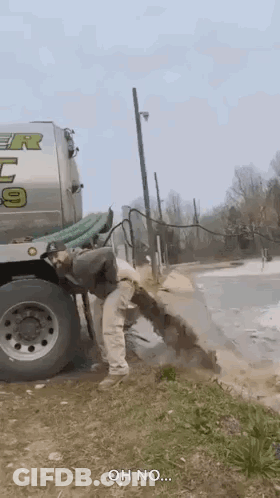 A Man Is Standing Next To A Septic Tank Truck . GIF