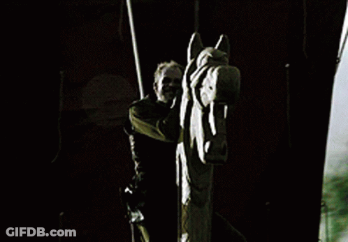 A Man Is Standing Next To A Statue Of A Horse Head GIF
