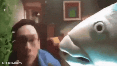 A Man Is Standing Next To A Stuffed Fish . GIF