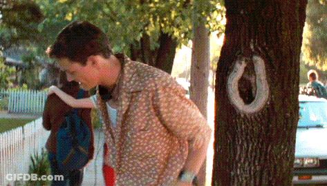 A Man Is Standing Next To A Tree With A Horseshoe Shaped Hole In It GIF