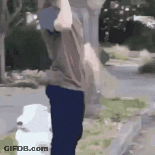 A Man Is Standing Next To A White Dog . GIF