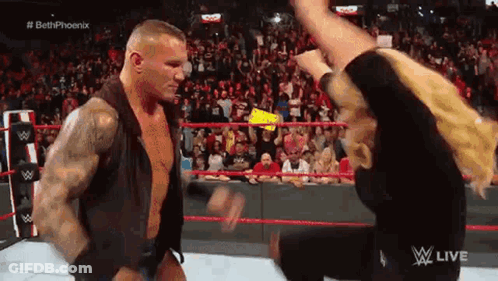 A Man Is Standing Next To A Woman In A Wrestling Ring . GIF