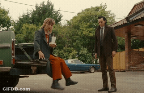 A Man Is Standing Next To A Woman Sitting In The Back Of A Truck . GIF