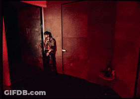 A Man Is Standing On A Balcony Looking Out At The City At Night GIF