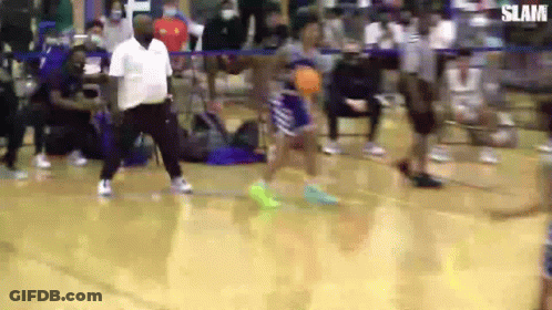 A Man Is Standing On A Basketball Court Watching A Player Shoot A Basketball . GIF