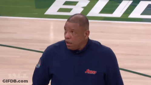 A Man Is Standing On A Basketball Court Wearing A Blue Axcu Shirt GIF