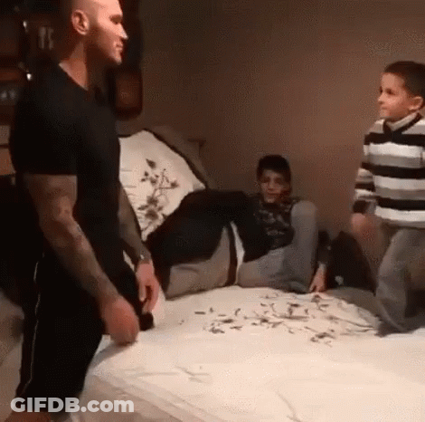 A Man Is Standing On A Bed Next To Two Boys . GIF