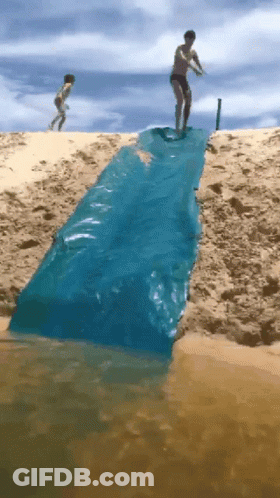 A Man Is Standing On A Blue Tarp That Is Going Into The Water GIF